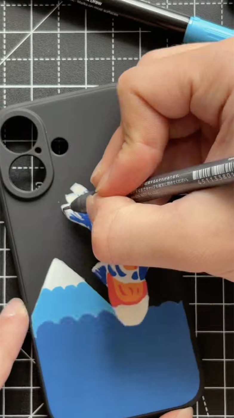 La mano di Federico che disegna a pennarello l’onda sulla cover nera del telefono, accanto al ritaglio di carta col Monte Fuji